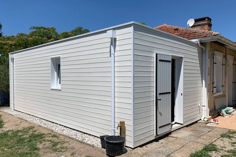 Extension en ossature bois avec bardage pré-peint blanc & toit plat en membrane EPDM à Ychoux